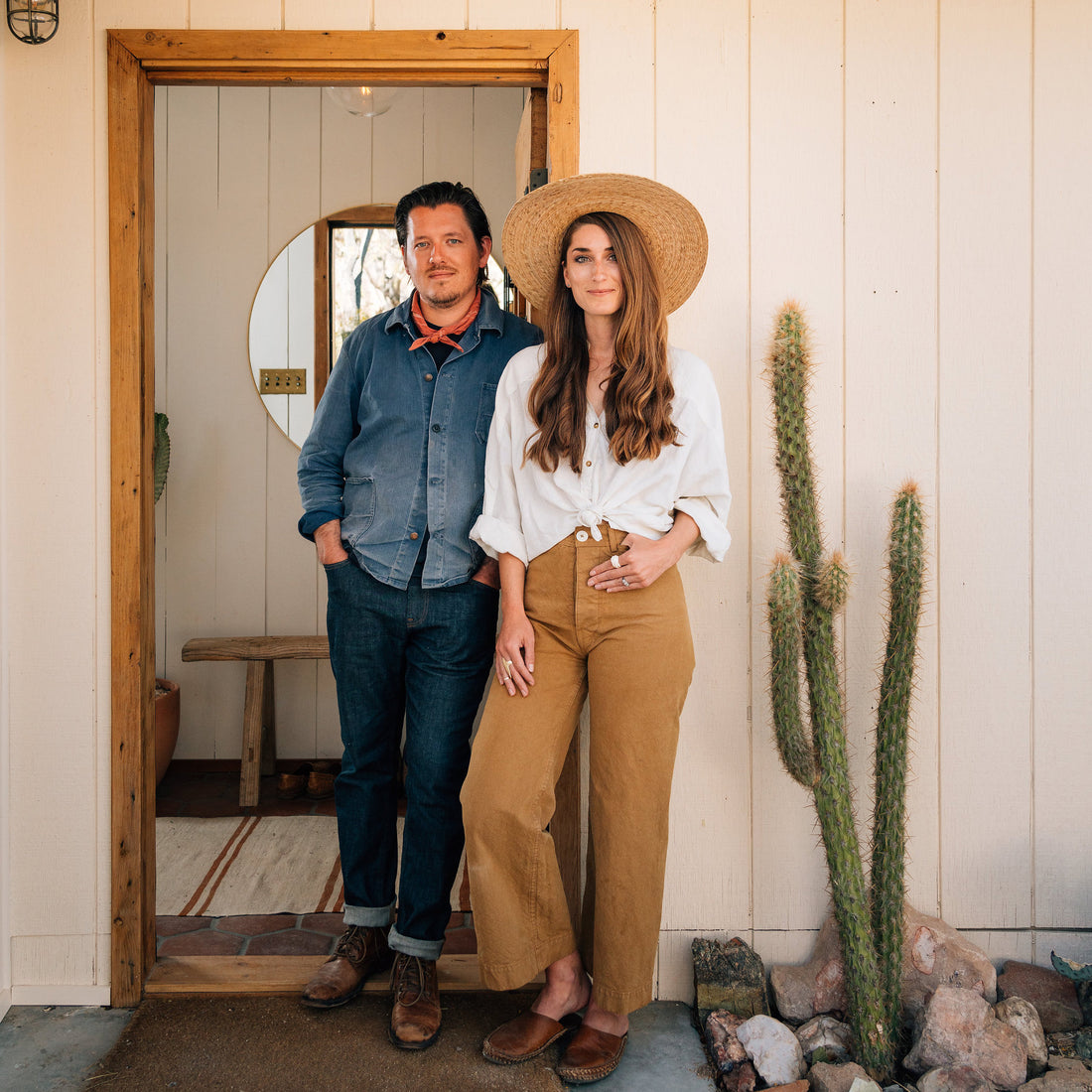 man and woman standing in front of a door with a cactus